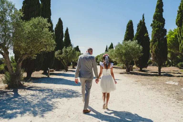 couple de mariés se tenant la main et marchant de dos dans un parc lors de la séance couple de leur mariage