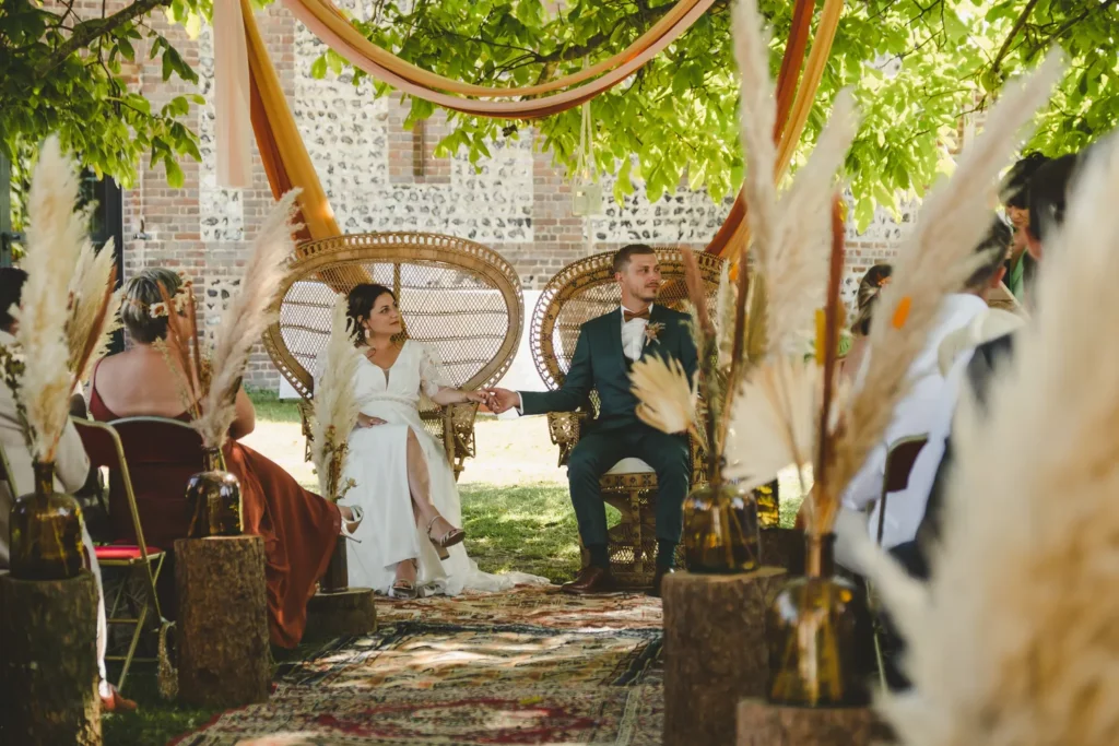 mariés assis se tenant la main en écoutant le discours de leurs proches pendant la cérémonie laique de leur mariage en normandie