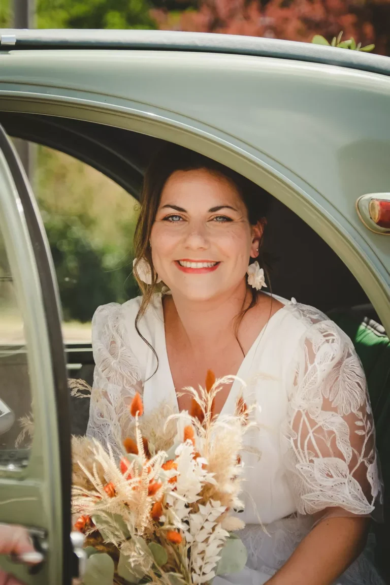 mariée tenant son bouquet et sortant de la voiture devant la mairie lors de son mariage bohème en normandie