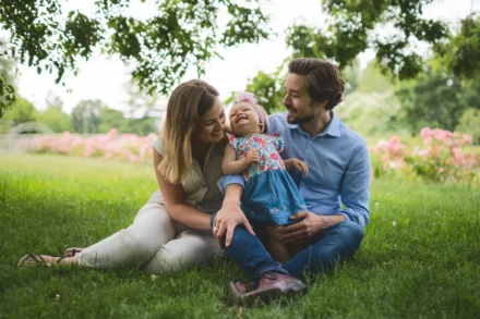 photo de famille de jeunes parents assis dans l'herbe avec leur petite fille