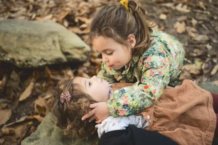 petite fille tenant sa petite soeur par la tête pour lui faire un bisou