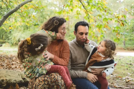 photo d'une famille de deux parents et leurs deux filles faisant des grimaces