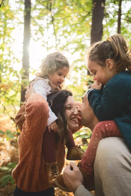 deux parents avec chacun une de leur fille sur les épaules dans une ambiance automnale