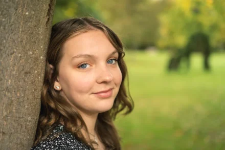 portrait d'une jeune fille adossée à un arbre en automne
