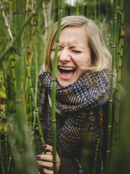 portrait automnal d'une jeune femme éclatant de rire entourée de bambous