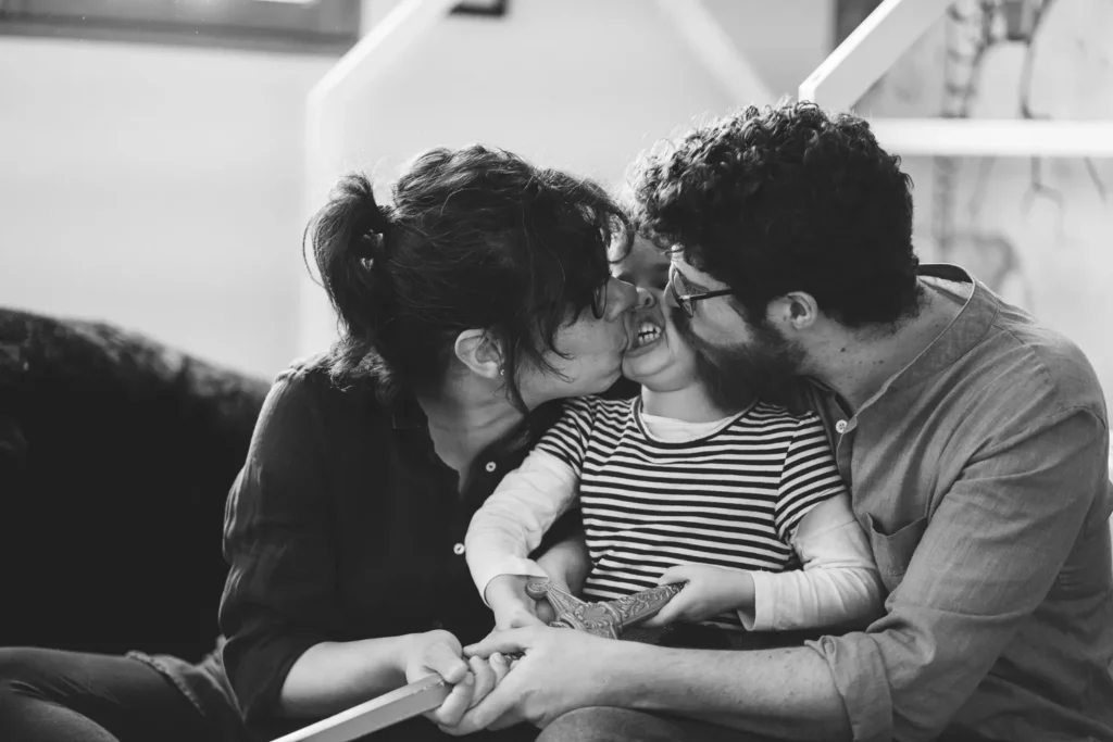 photographie de famille noir et blanc à rouen avec les parents qui font un bisou à leur fille