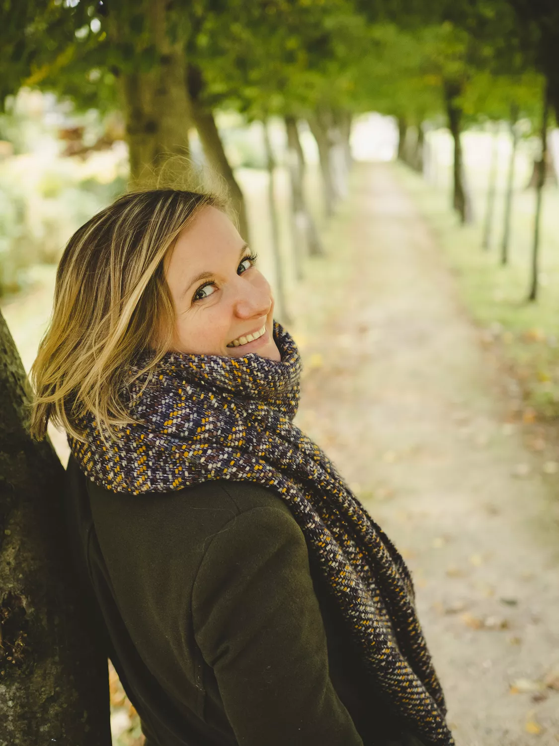 portrait automnal d'une jeune femme contre un arbre dans l'allée d'un parc en normandie