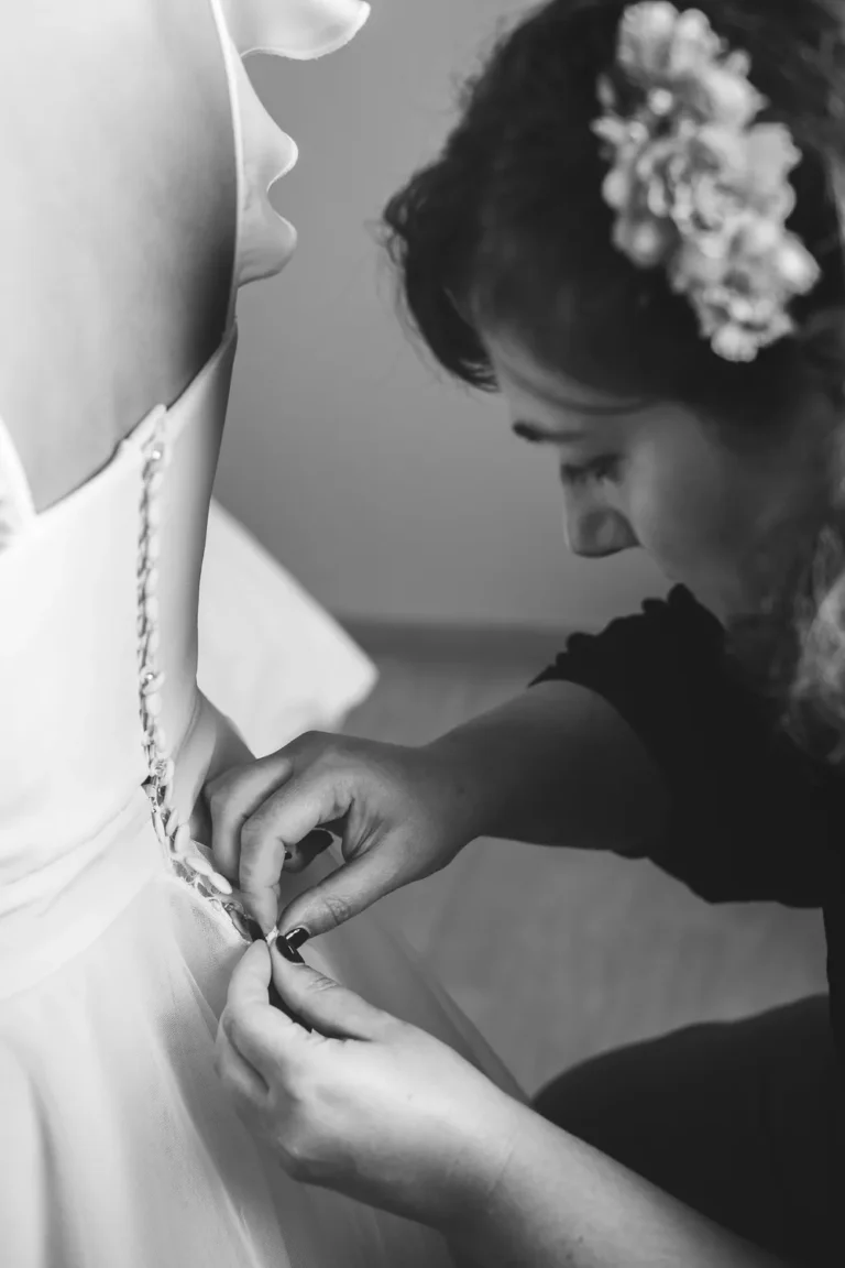 témoin de la mariée qui boutonne sa robe par un photographe de mariage à rouen