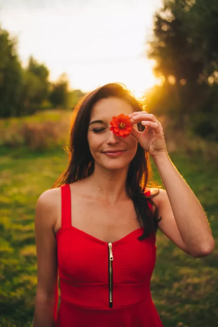 portrait femme qui se met une fleur devant l'oeil gauche au coucher du soleil