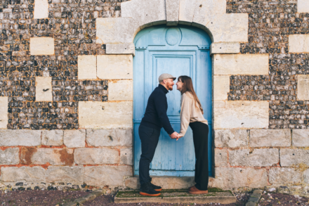 couple se tenant la main et se regardant avec amour devant une porte bleue